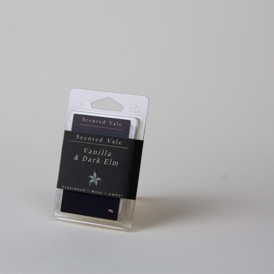 Scented Vale Vanilla & Dark Elm wax melts in a clear plastic clamshell package with a dark paper band label, photographed on a light grey background.
