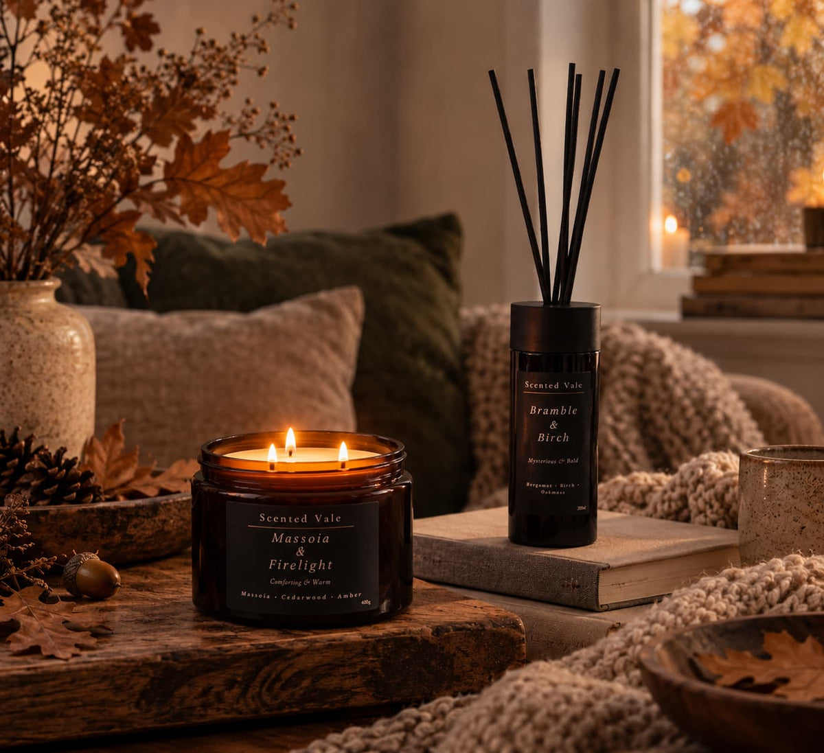 Three-wick candle and reed diffuser styled in a cosy autumn living room with warm woods and natural textures.