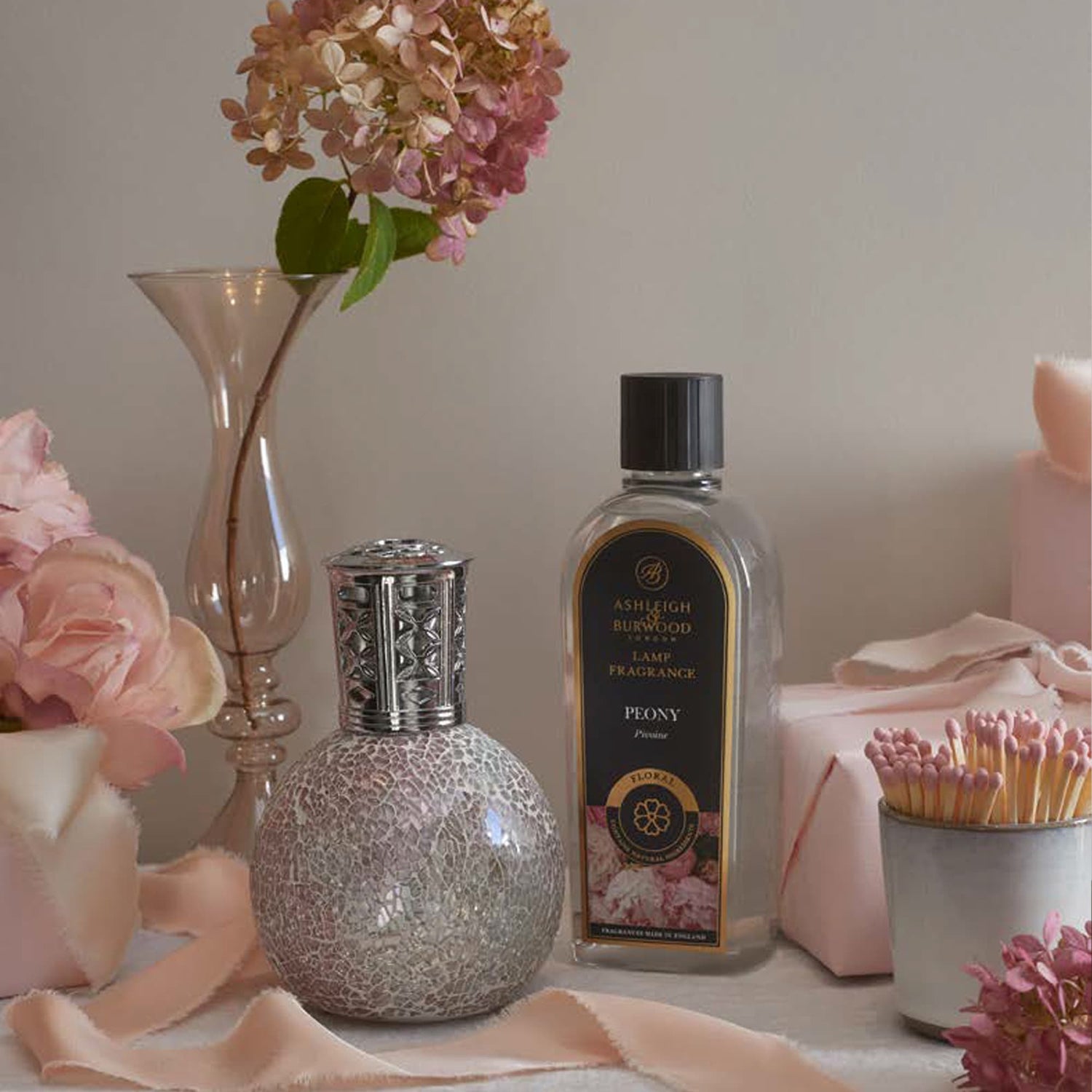 Fragrance Lamp and Lamp Fragrance on a pale background with pink accessories