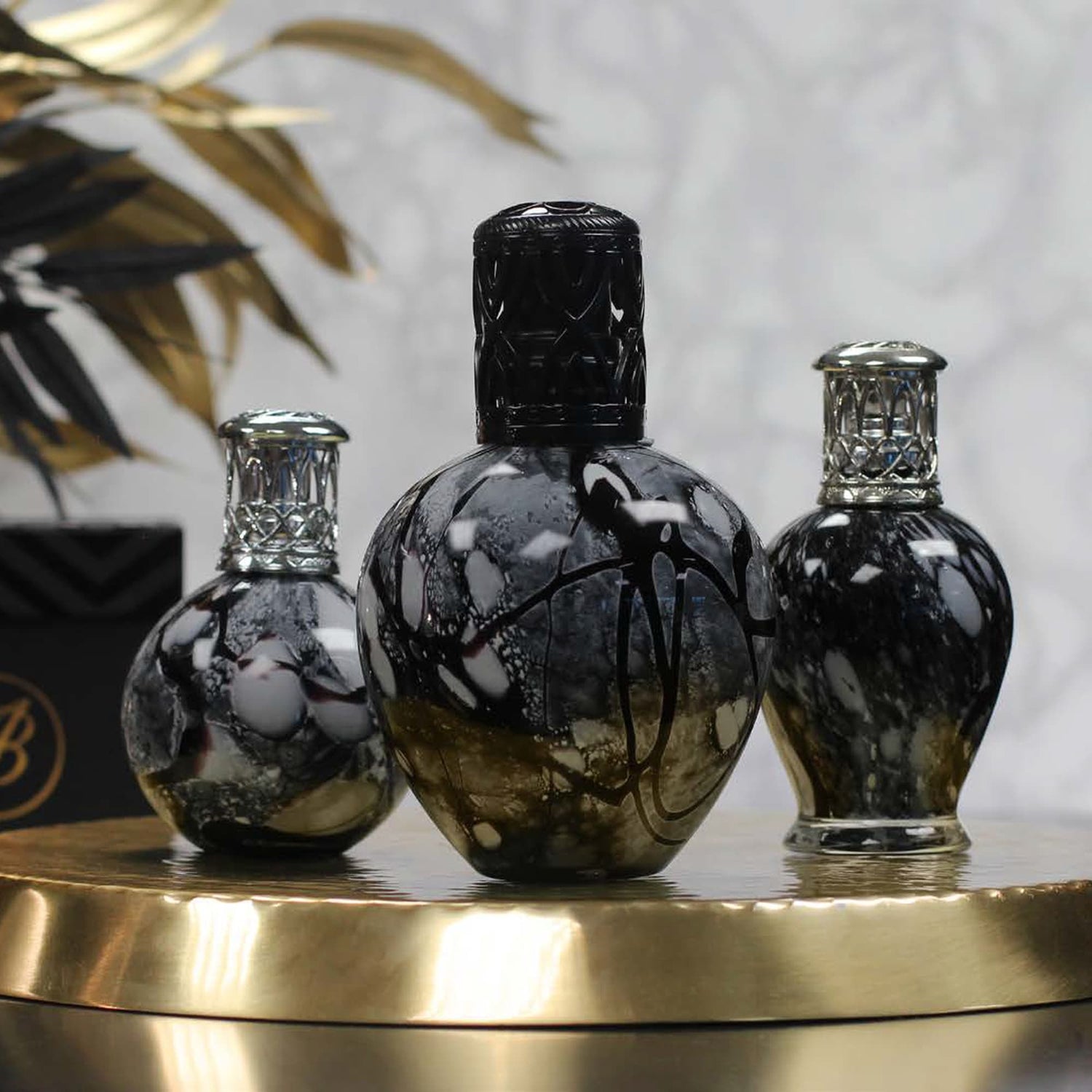 A range of 3 different sized fragrance lamps in black marble effect on a gold tray