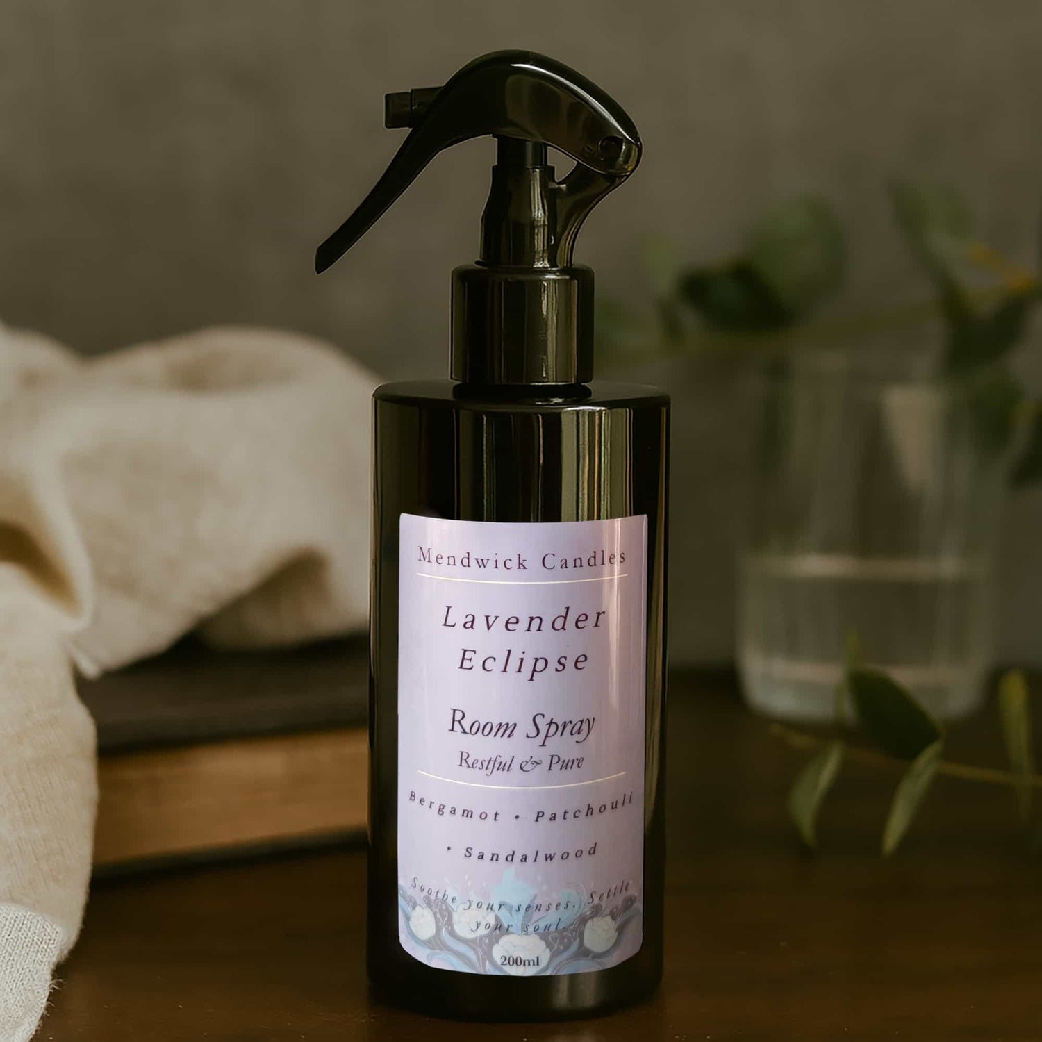 Lavender Eclipse Room Spray on a dark wood taple with soft linen fabric
