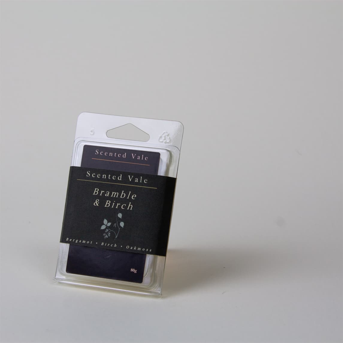 A packaged scented wax melt labelled 'Scented Vale Bramble & Birch' in a clear plastic sleeve with a dark paper band  and, photographed on a plain light grey background.