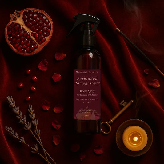 Forbidden Pomegranate room spray lay on a red velvet background with pomegrantes and lit candle. Intimate feeling